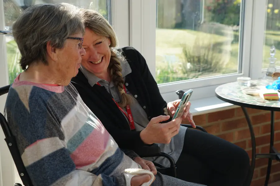 Carer showing an older woman how care information can be accessed on a smartphone